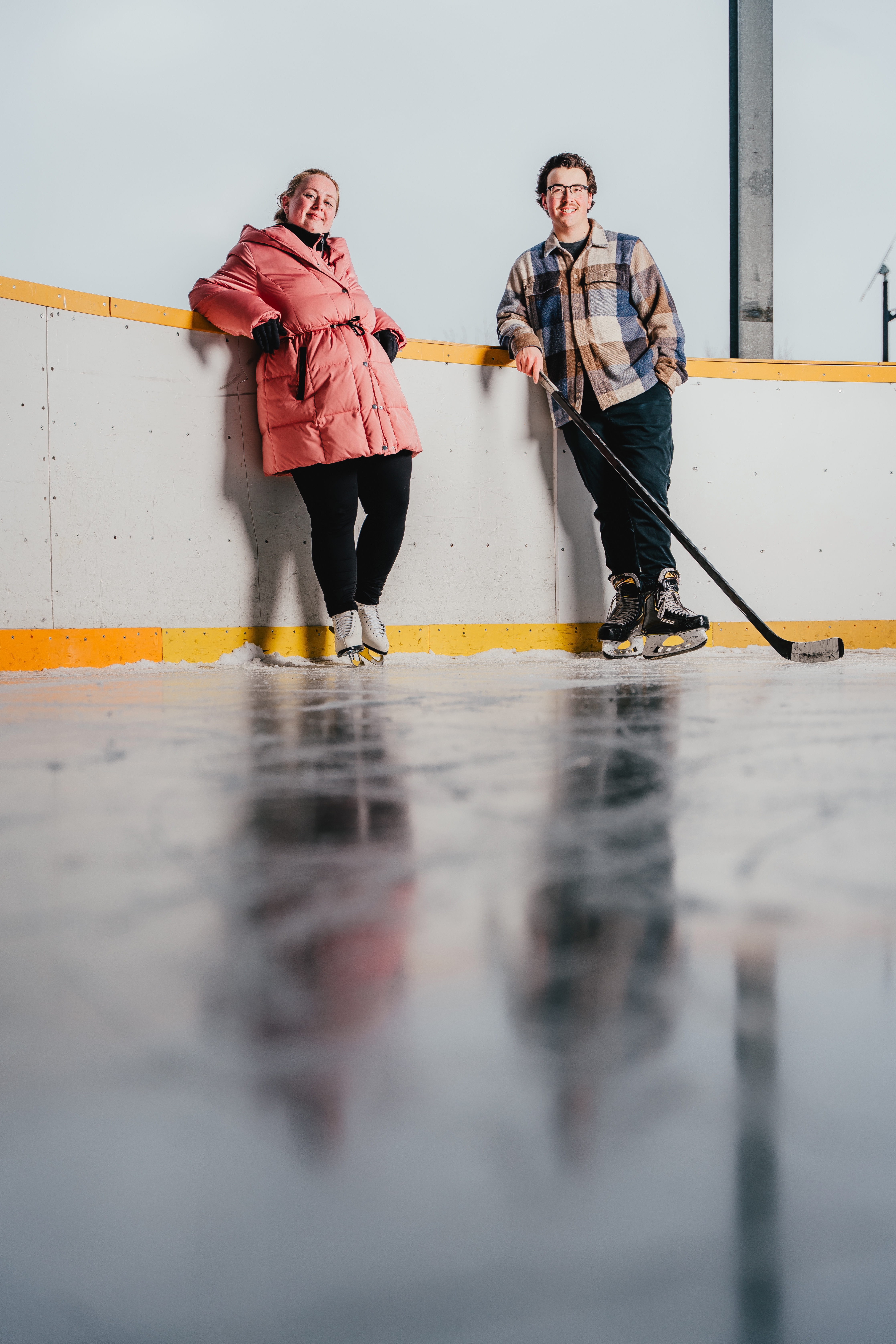A man and woman pose on an outdoor skating rink