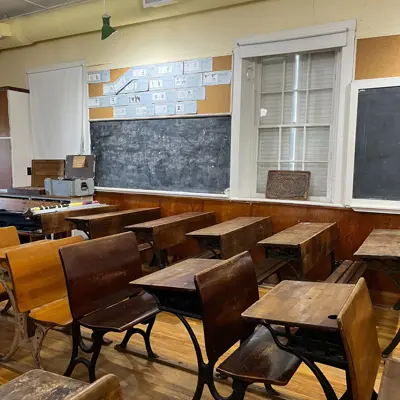 old historic school room featuring desks and a chalkboard