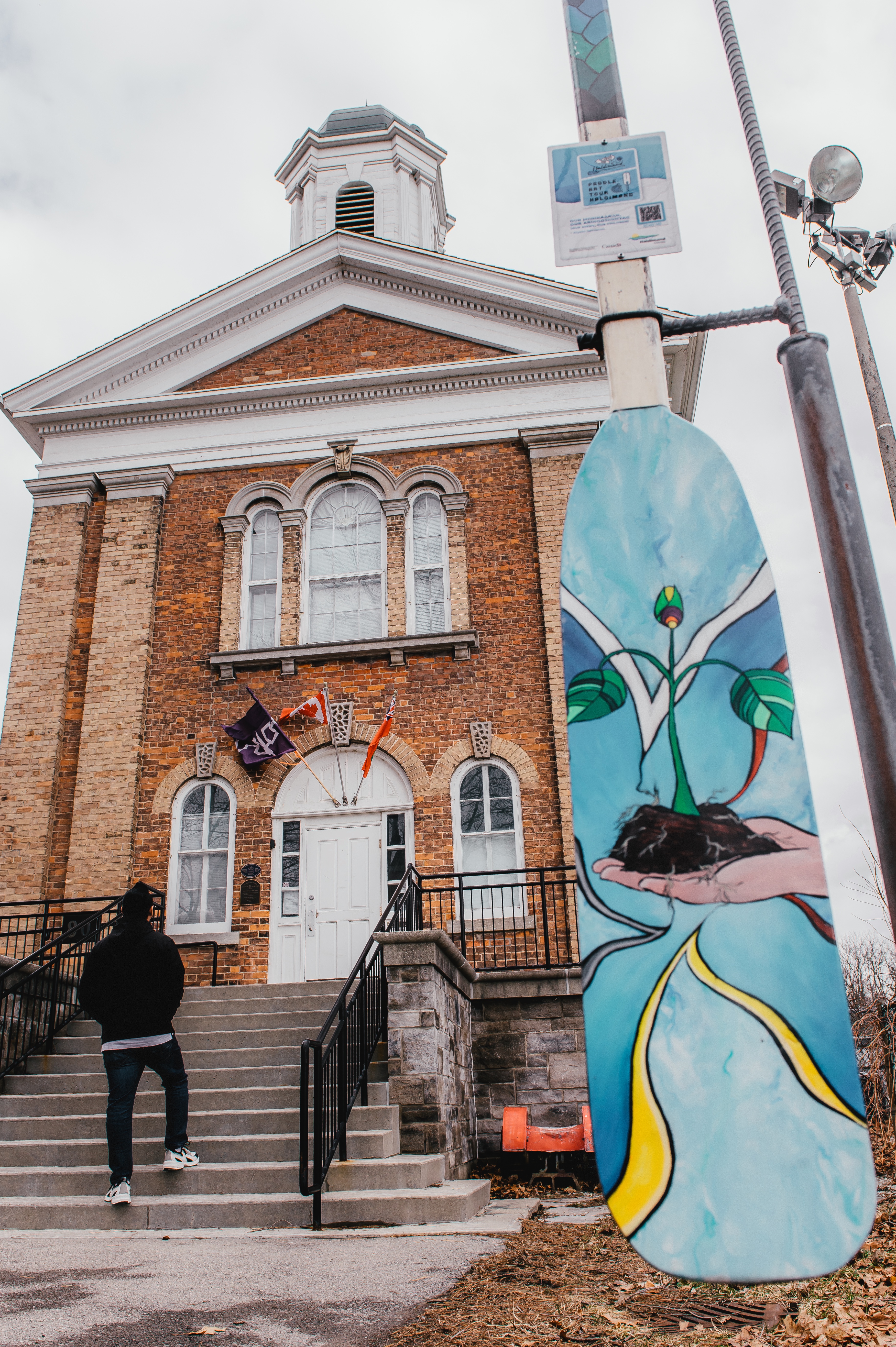 A colourful painted paddle on display in front of a museum