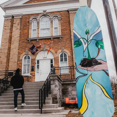 A colourful painted paddle on display in front of a museum