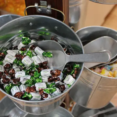 A silver bucket with wrapped candy in it and a large scoop