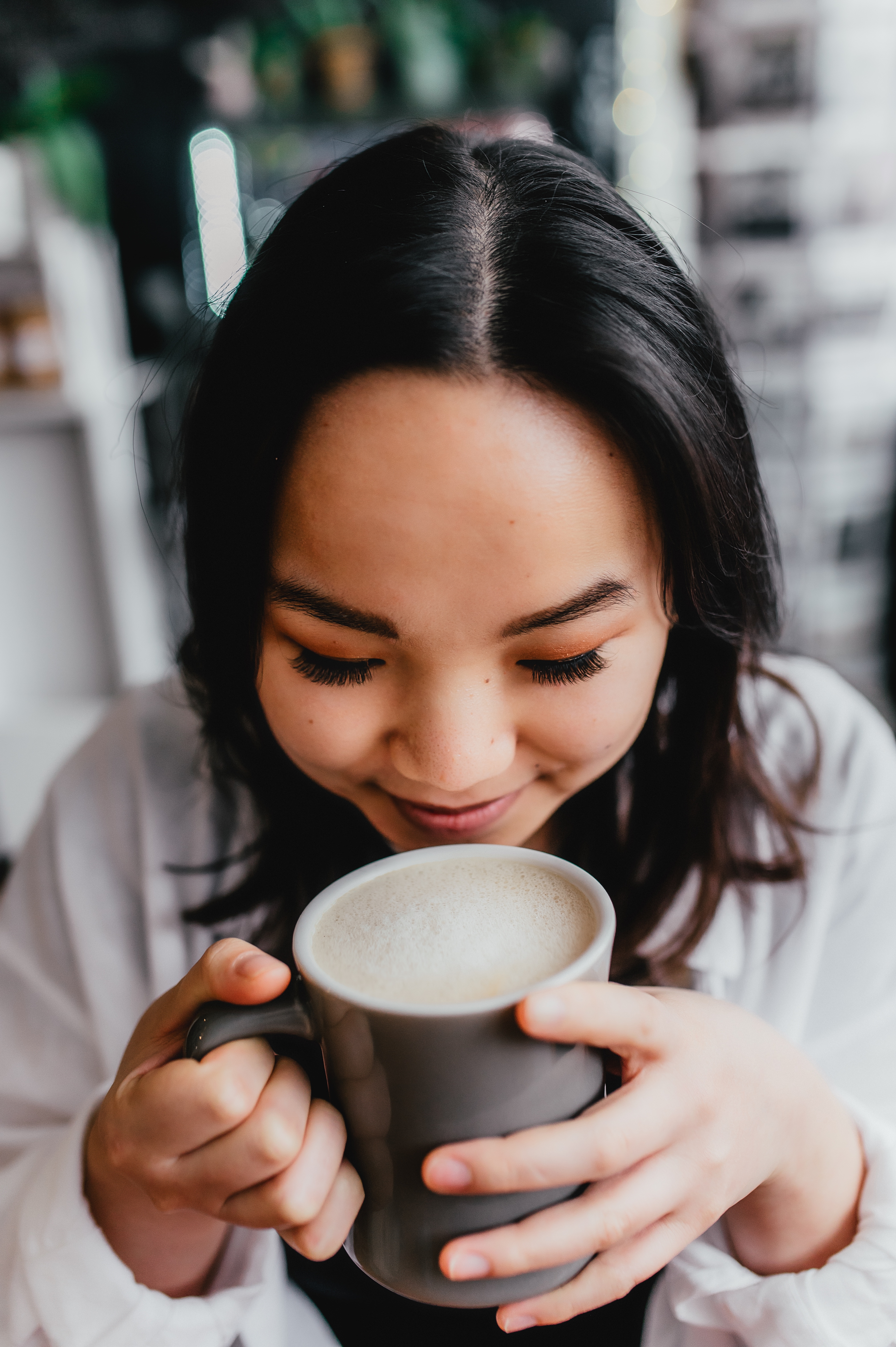 A woman holds a coffee under her nose