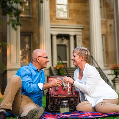 A man and woman share a toast over a picnic basket