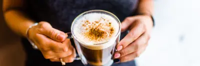 woman holding a glass coffee cup