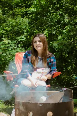 Young women sit around a campfire roasting marshmallows
