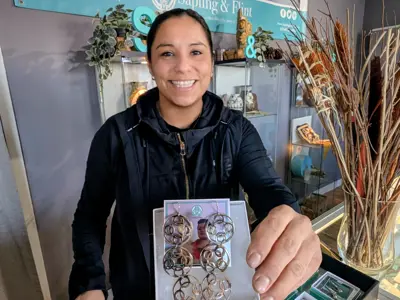 A woman proudly holds hand crafted earrings