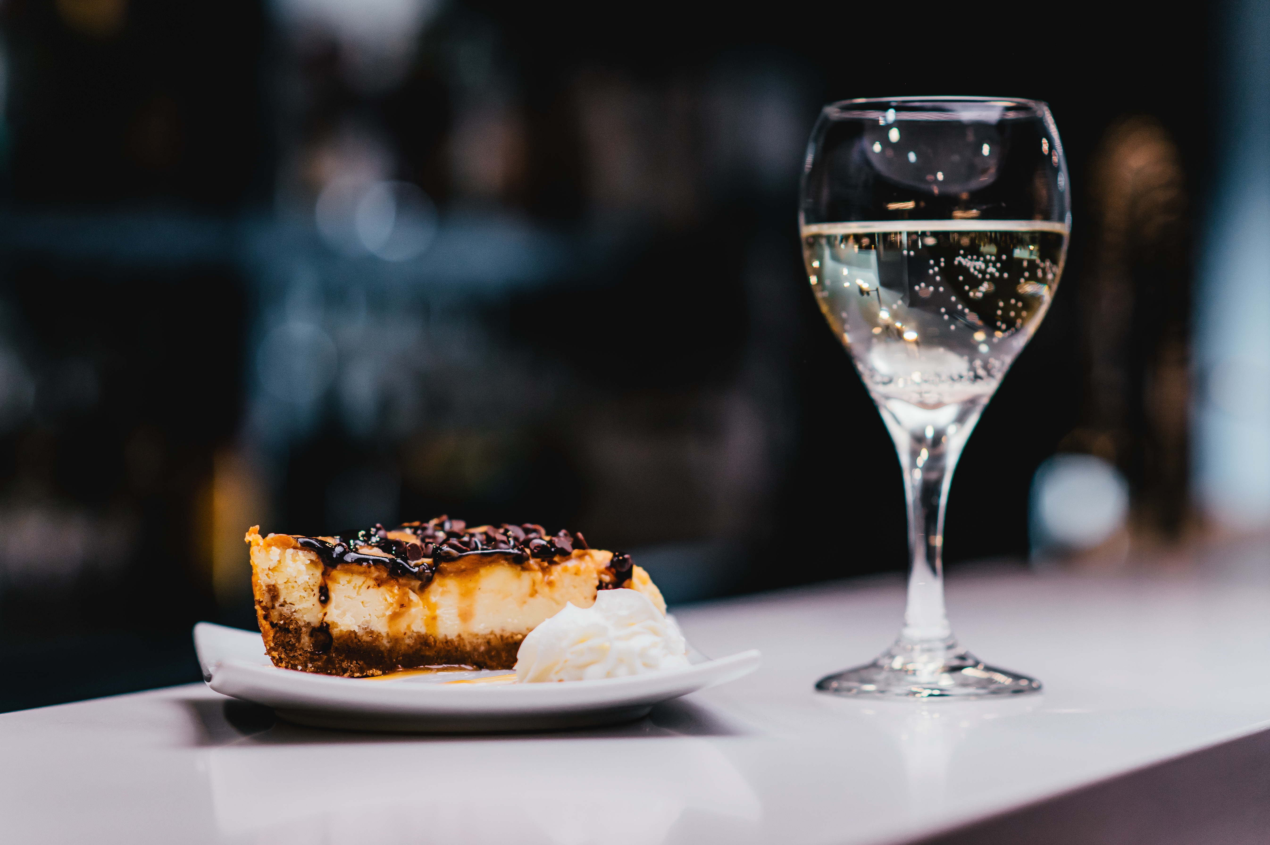 A dessert sits atop a china plate next to a glass of wine