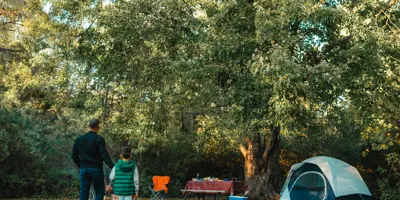 man and boy walking away towards a tent 