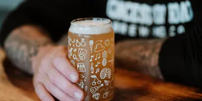 Hand holding a beer on a pub table