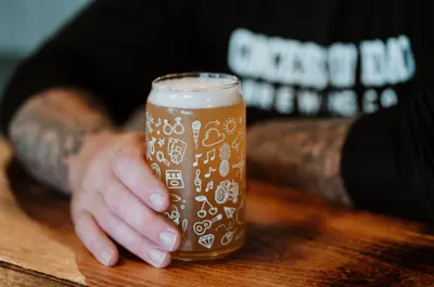 Hand holding a beer on a pub table