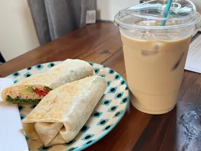 iced coffee with wrap on a plate beside it
