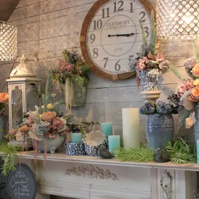 various vases and candles on a mantel in a shop with a clock behind