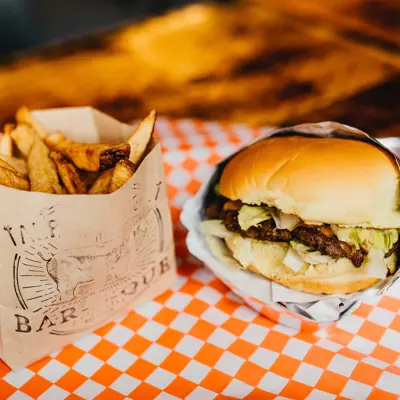 an order of fries in a bag beside a burger