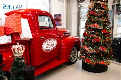 A vintage red truck sits in a showroom decorated for the holidays									