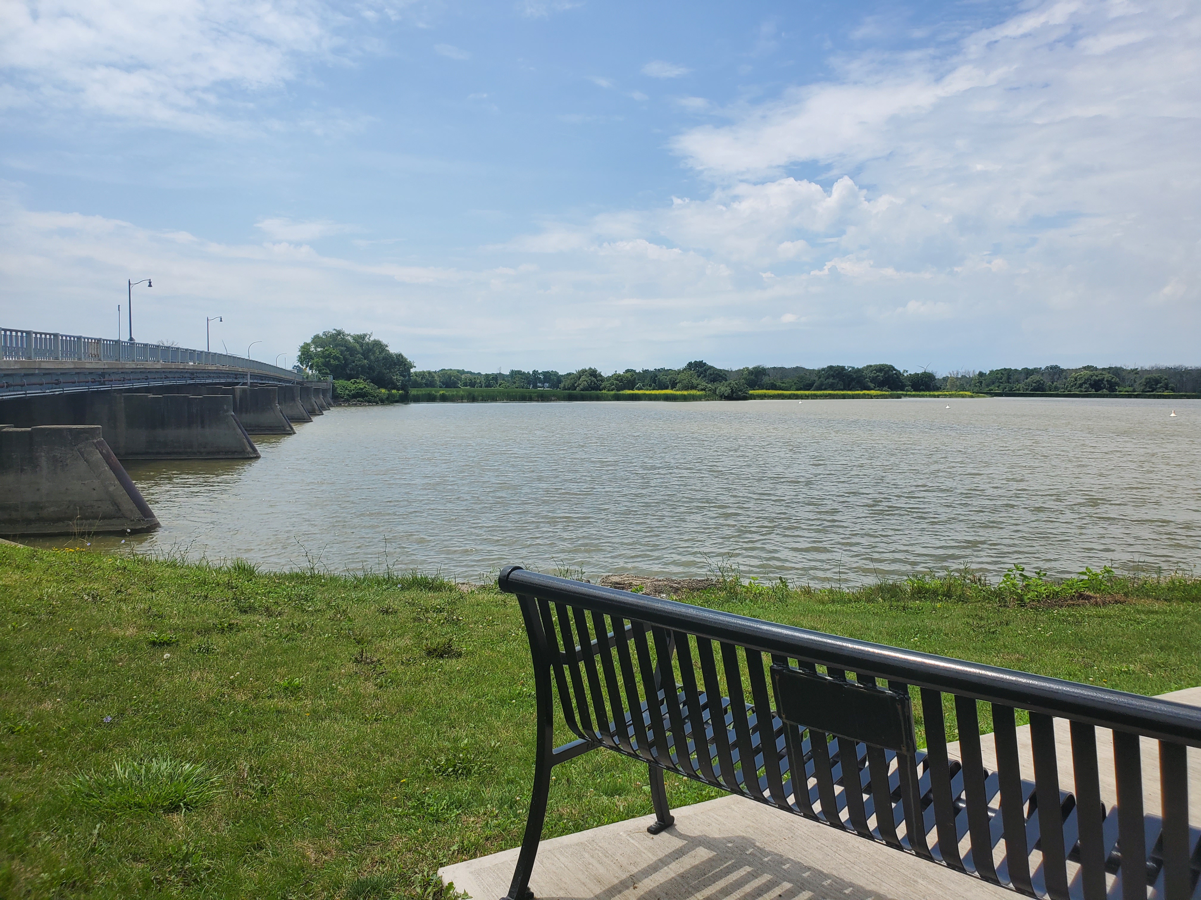 A bench sits in front of the Grand River and Dunnville Bridge
