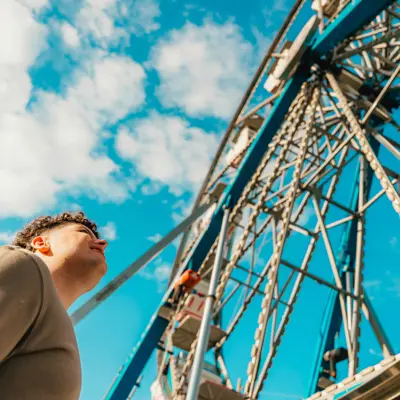 picture of man looking up at a ferris wheel