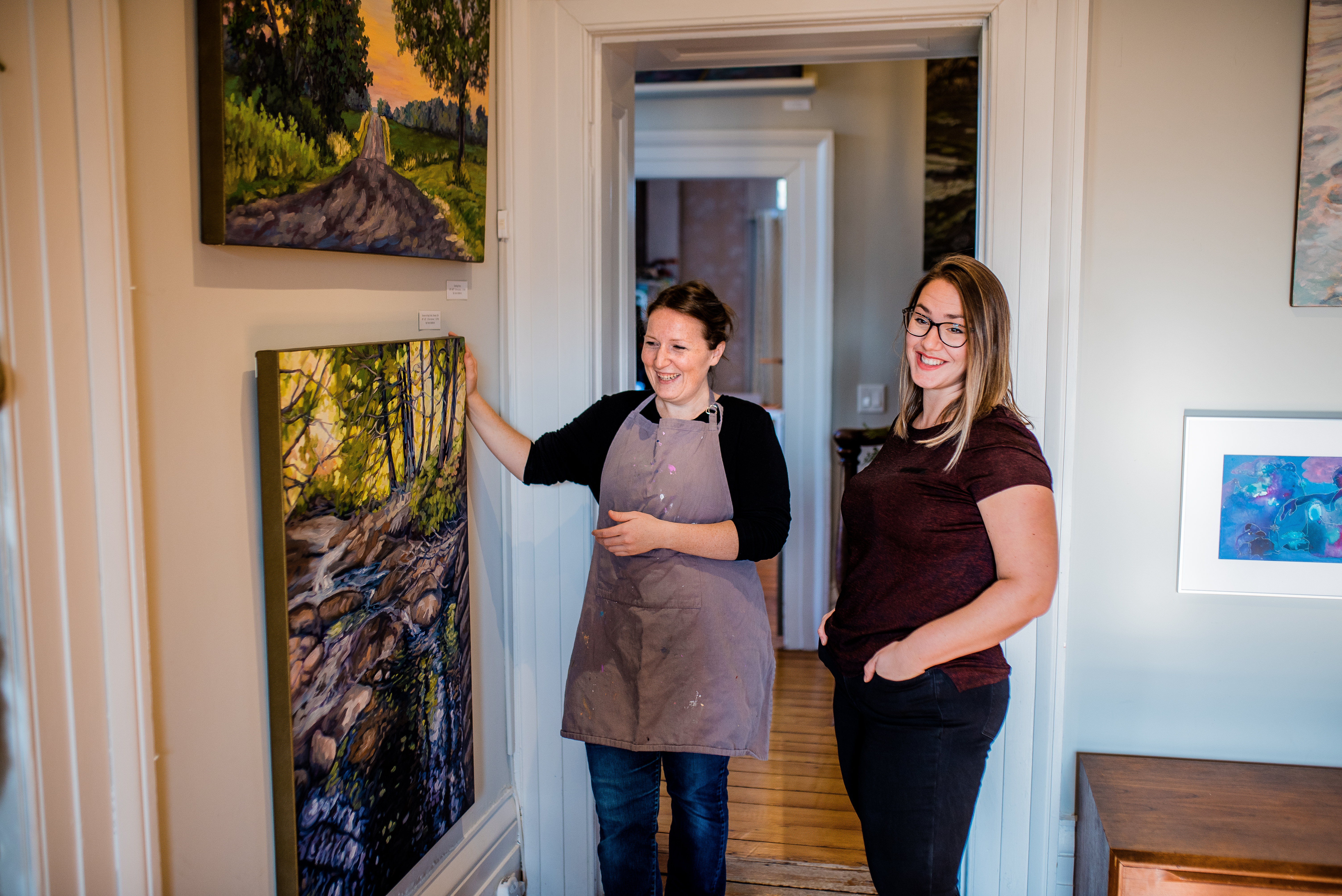 2 women looking at art on wall of art gallery