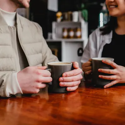 two people sitting down holding mugs 