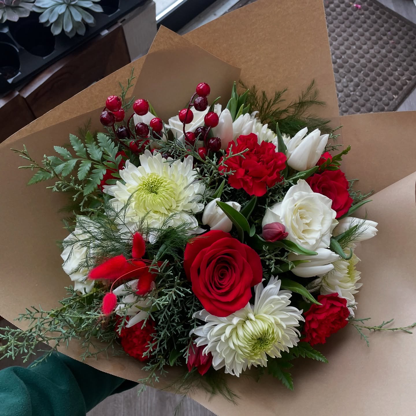a bouquet of red and white flowers with red berries for the holidays