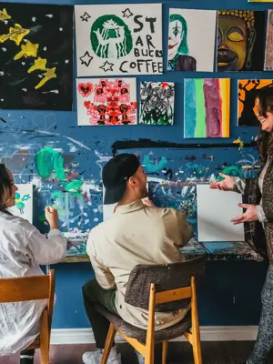 Looking from the back at a couple taking an art class with a teacher