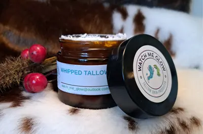 An open container of whipped tallow cream sits on a cow hide